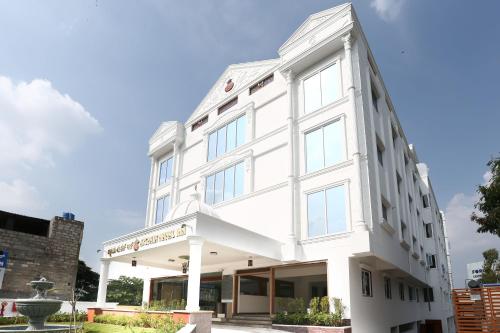 un edificio blanco con una fuente frente a él en Treebo Trend Akshaya Mahal Inn, en Mysore
