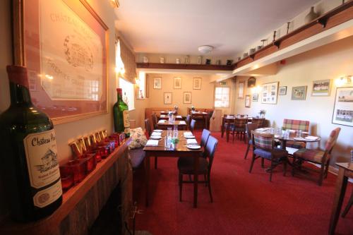 a restaurant with tables and chairs and a bottle of wine at Worsley Arms Hotel in Hovingham