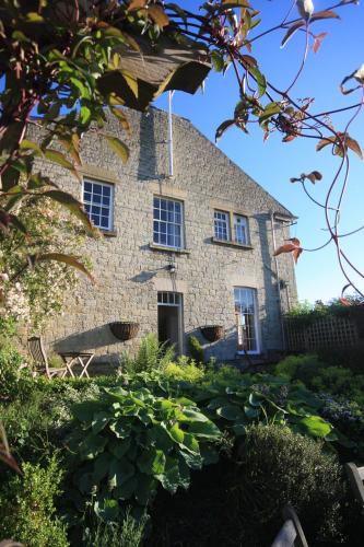 an old stone house with a garden in front of it at Worsley Arms Hotel in Hovingham