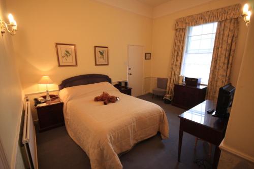 a bedroom with a bed with a teddy bear on it at Worsley Arms Hotel in Hovingham
