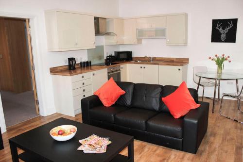 a living room with a black couch and a kitchen at Princes Dock Chambers 3 in Hull