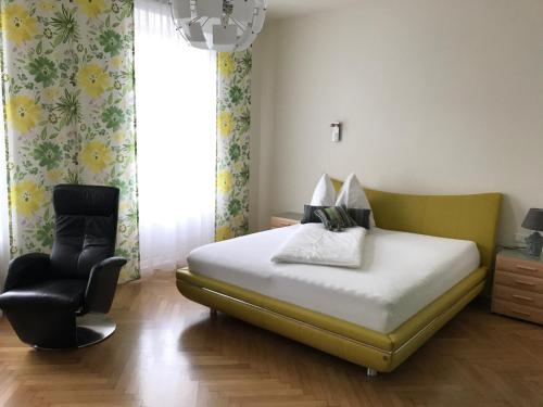 a bedroom with a bed and a chair and a window at Hotel Bellini in Leoben