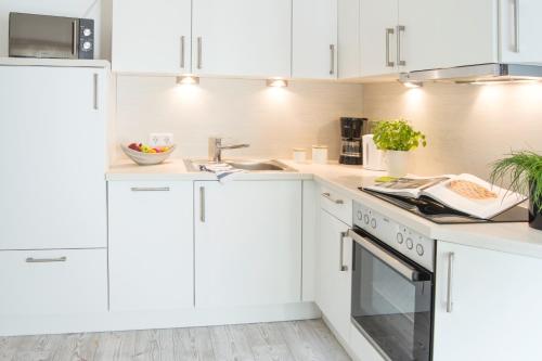 a white kitchen with white cabinets and a sink at Möwennest in Flensburg