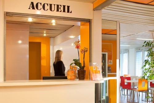 a woman is standing in the lobby of a restaurant at FAST HOTEL Les Ulis - Courtabœuf in Les Ulis