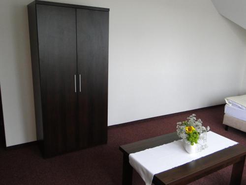 a room with a cabinet and a table with flowers on it at Hotel Cynamon in Tokarnia