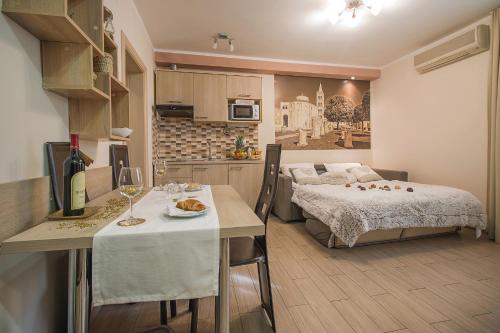 Holiday Center Ivona في زادار: غرفة مع سرير وطاولة مع كؤوس للنبيذ