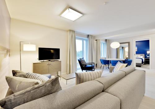 a living room with a large couch and a television at DORMERO Strandapartments Rügen in Binz