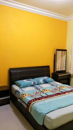 a bed in a room with a yellow wall at Rose Apartment Kea Farm in Cameron Highlands