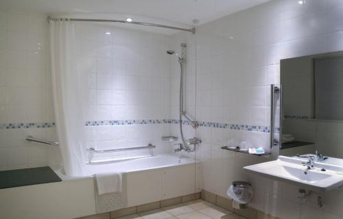 a bathroom with a bath tub and a sink at Holiday Inn Chester South, an IHG Hotel in Chester