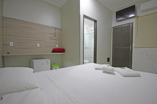 a bedroom with a white bed with two towels on it at Pousada Recanto da Morada in Olímpia