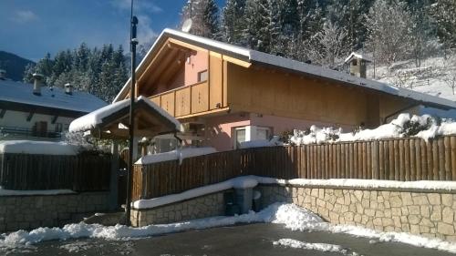 a house covered in snow in front of a fence at Pit Stop Cadore in Valle di Cadore