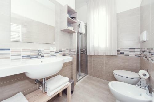 a white bathroom with a sink and a toilet at Luccainn in Lucca