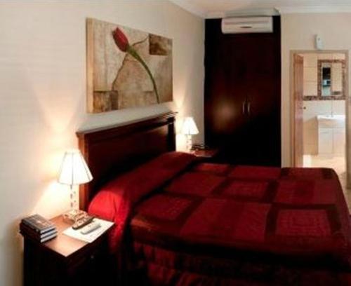 a bedroom with a red bed and a table with a lamp at Rustenburg Boutique Hotel in Rustenburg