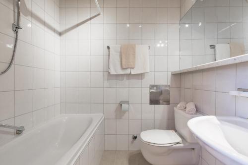 a white bathroom with a tub and a toilet and a sink at Hotel Rogen in Neustift im Stubaital