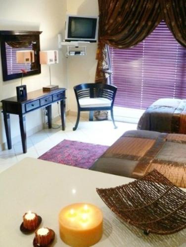 a bedroom with a bed and a desk with a television at Rustenburg Boutique Hotel in Rustenburg
