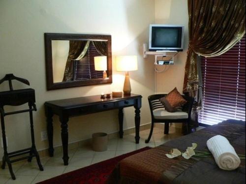 a bedroom with a desk and a television and a bed at Rustenburg Boutique Hotel in Rustenburg