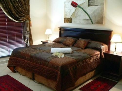 a bedroom with a large bed with two lamps on it at Rustenburg Boutique Hotel in Rustenburg
