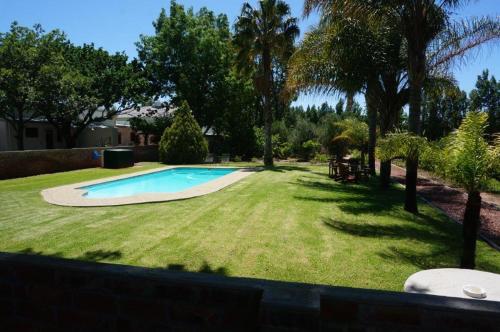 a swimming pool in a yard with trees and grass at Long Acres Cottages in Montagu