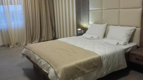 - une chambre dotée d'un grand lit avec des draps et des oreillers blancs dans l'établissement Guesthouse Nikolić, à Negotin