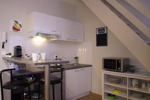 une cuisine avec des placards blancs et un comptoir avec un four micro-ondes dans l'établissement L'Esquile by Cocoonr, à Toulouse