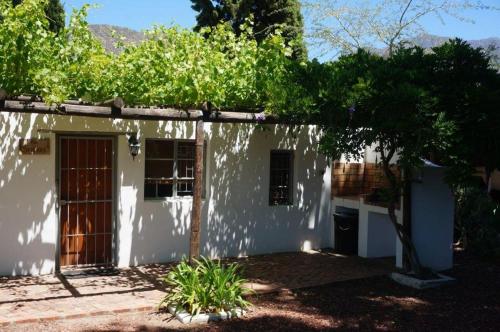a white house with a tree in front of it at Long Acres Cottages in Montagu
