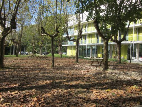 a park with picnic tables and trees in front of a building at UBA Hostel in Donostia-San Sebastián