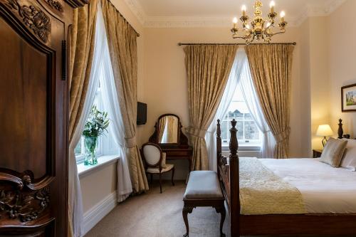 a bedroom with a bed and a chair and windows at Doxford Hall Hotel And Spa in Chathill