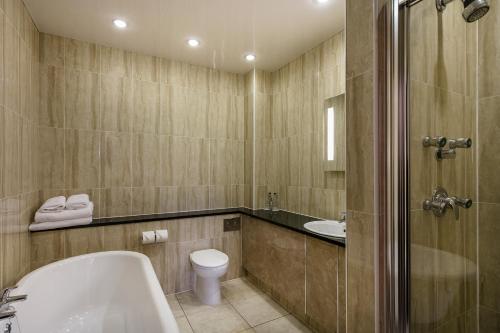 a bathroom with a tub and a toilet and a sink at Doxford Hall Hotel And Spa in Alnwick