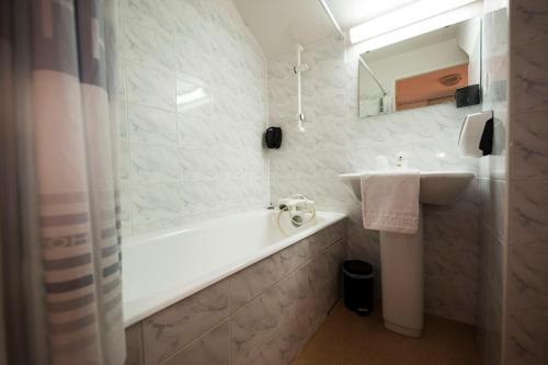 a white bathroom with a sink and a tub and a sink at Auberge de Motz in Motz
