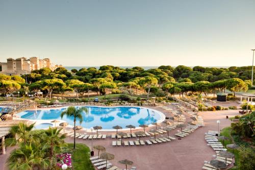 vistas a la piscina, a las sillas y a los árboles en Barceló Punta Umbría Beach Resort, en Punta Umbría