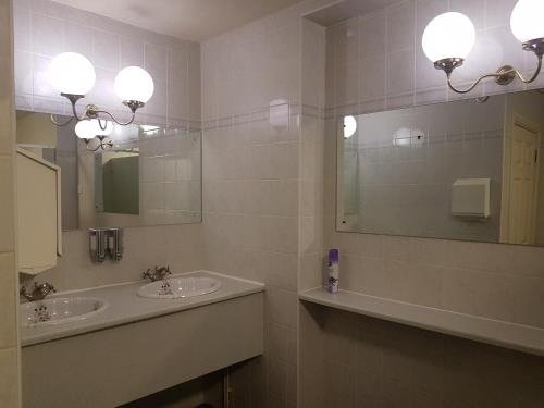 La salle de bains est pourvue de 2 lavabos, d'un miroir et d'une baignoire. dans l'établissement Millgate House Hotel, à Newark-on-Trent