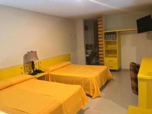 a hotel room with two beds and a television at Palacio Rojo Hotel Familiar in Morelia