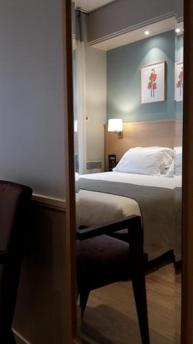 a bedroom with a large bed and a mirror at Hôtel Magellan in Paris