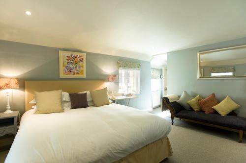 Un dormitorio con una gran cama blanca y un sofá. en The Greyhound on the Test Hotel, en Stockbridge