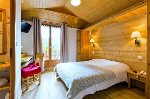 a bedroom with a bed in a room with wooden walls at Logis Hotel Gai Soleil in Samoëns