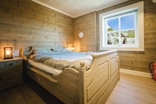 uma cama num quarto de madeira com uma janela em Lastølen 3 bedrooms em Brunstad