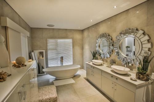 a bathroom with a tub and a sink and mirrors at Sea Dreams Guesthouse in Ballito