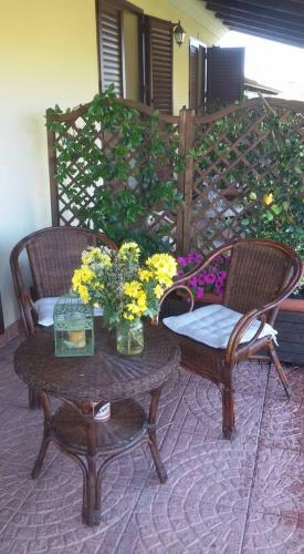 two chairs and a table with flowers on a patio at Agriturismo Sa Mendhula in Cugnana