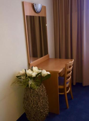 a table with a mirror and a vase of flowers at Hotel Luna in Žiar nad Hronom