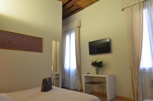 a bedroom with a bed and a television and a window at Albergo al Tiepolo in Venice