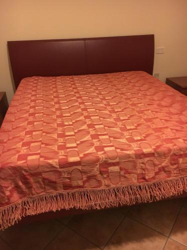 a bed with a orange comforter on top of it at Residence K.B. 2 in Fano