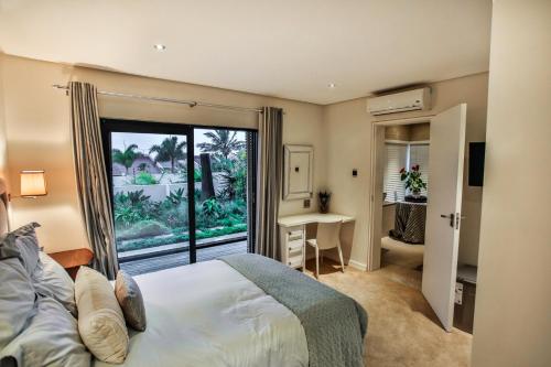 a bedroom with a bed and a large window at Sea Dreams Guesthouse in Ballito