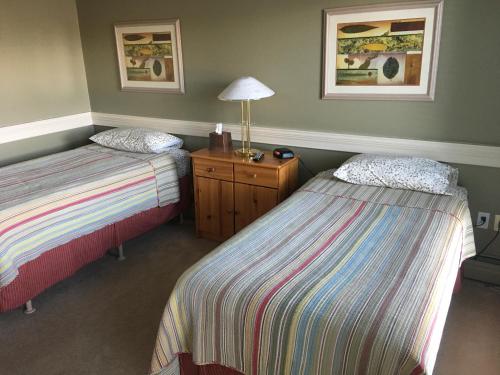 Habitación con 2 camas y mesa con lámpara. en Laura's Lodge en Saskatoon