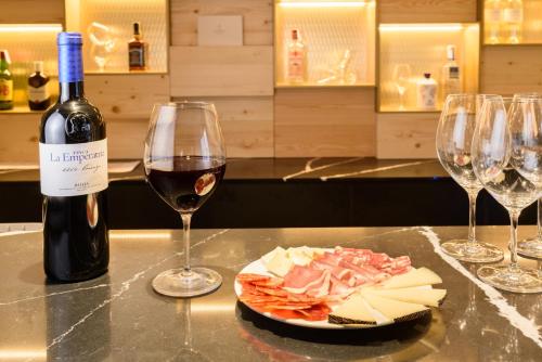a bottle of wine and a plate of cheese and wine glasses at Eurostars Fuerte Ruavieja in Logroño