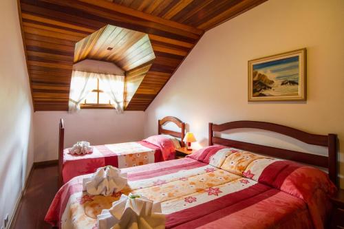 Dos camas en una habitación con techos de madera. en Pousada Serena, en Campos do Jordão