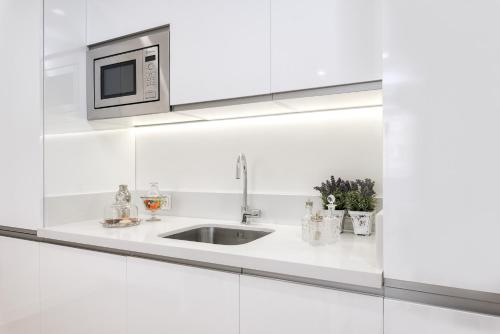 a white kitchen with a sink and a microwave at iloftmalaga Centro Alameda in Málaga