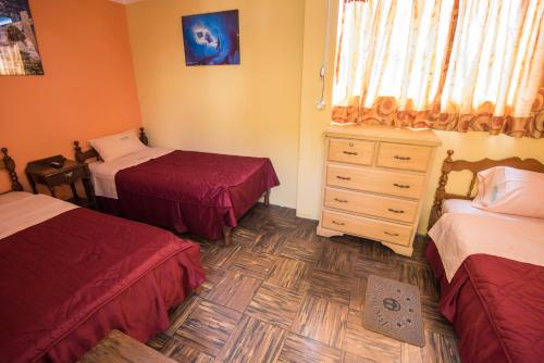 a bedroom with two twin beds and a dresser at Hotel Galaxia in Huaraz