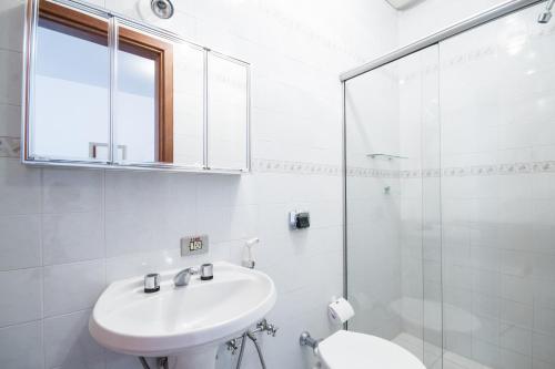 Un baño blanco con lavabo y ducha. en Pousada Serena, en Campos do Jordão