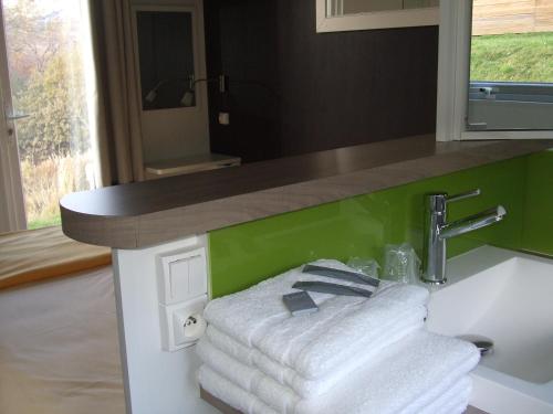 a bathroom with a sink with towels under a counter at Camping-Hotel de Plein Air Les 2 Bois in Baratier