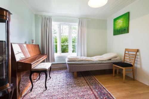 Rasmusgarden في ستراندا: غرفة فيها بيانو وسرير ونافذة